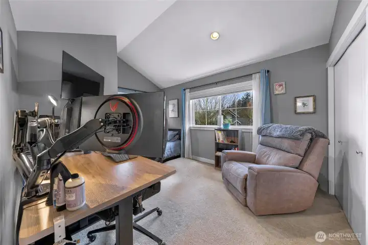 Spacious third bedroom or flex room with vaulted ceilings, large window, and plenty of space for work or relaxation.