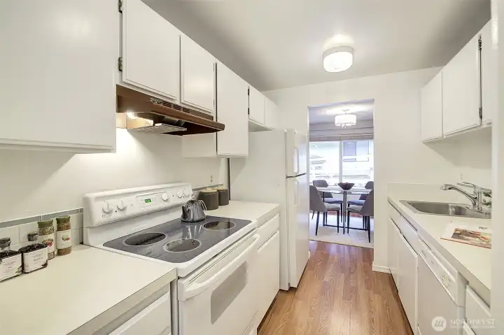 The freshly painted galley kitchen has plenty of cabinetry, nice appliances and lots of counter space.  Note the wood plank flooring runs through the kitchen into the dining area.