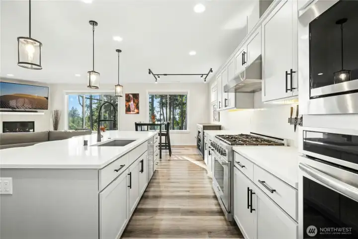 The beautifully designed kitchen features sleek cabinetry, modern appliances, and abundant counter space, all centered around a generous island ideal for gathering. Large windows frame serene views, bringing natural light and the beauty of the outdoors into this inviting, functional space.