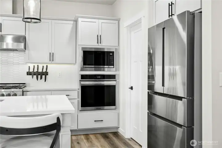 The kitchen is equipped with stainless steel appliances, including a built-in microwave and second oven, seamlessly integrated into sleek cabinetry. Clean lines, modern finishes, and smart storage create a polished, highly functional cooking space.