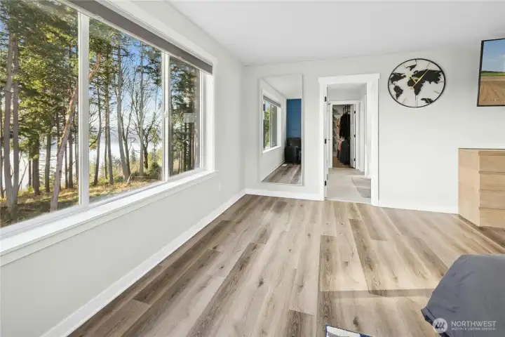 The spacious primary bedroom offers a tranquil retreat with large windows framing serene tree and water views. Thoughtful design and updated finishes create a light, airy space that feels both comfortable and refined.
