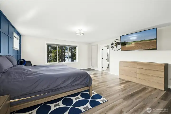 The primary bedroom offers generous space, modern finishes, and a calming color palette highlighted by a stylish accent wall. Large windows bring in natural light and peaceful Northwest views, creating a true retreat.