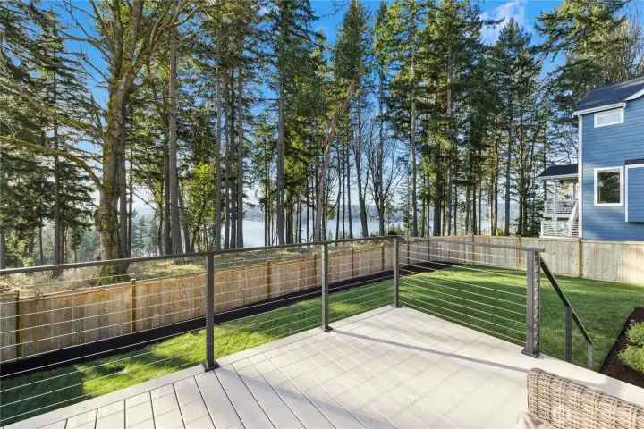 This elevated deck captures beautiful, filtered water views framed by towering evergreens, creating a serene and private outdoor setting. With modern cable railing and low-maintenance decking, it’s an ideal spot for dining al fresco, relaxing with a book, or entertaining while enjoying the peaceful Northwest backdrop and glimpses of the water beyond.