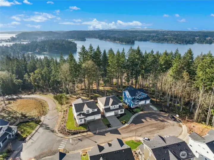 This wide aerial view puts the setting into perspectivene, nestled between a quiet cul-de-sac. The home enjoys a rare sense of openness with water vistas stretching beyond the tree line. The location that feels serene and scenic, yet comfortably connected to a well-planned community.