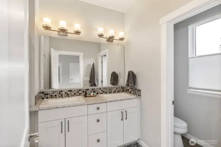 Spa-like primary bath with double vanities, tile flooring and spacious shower.