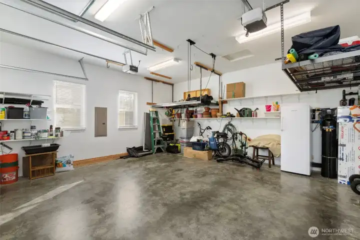 The oversized double garage features high ceilings with windows along the side and overhead for so much light. Two hanging storage racks and built-in shelving, as well as a whole house water purification system (along the back wall) complete the package.