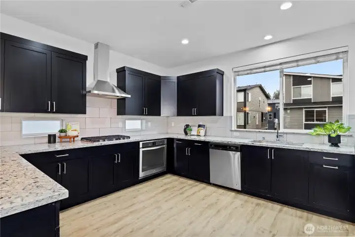 Large format Subway tile backsplash with SS hood vent gas range Quarz slab counters