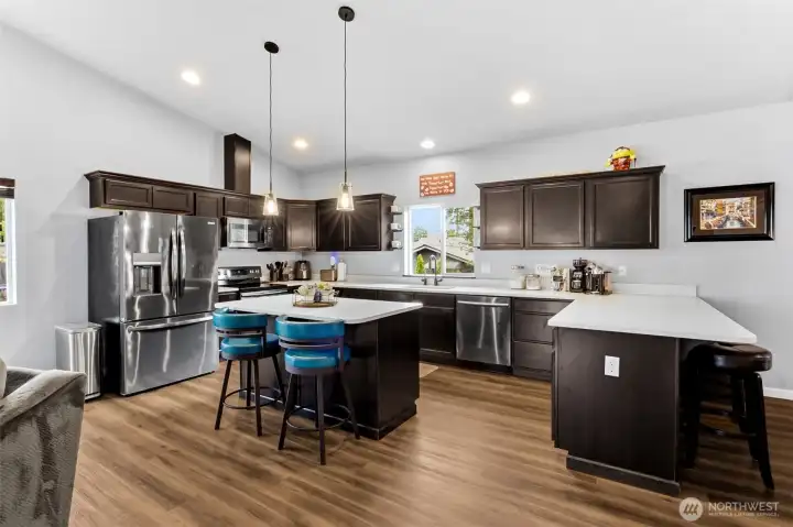 Beautifully upgraded kitchen featuring quartz countertops, stainless steel appliances, designer lighting, and generous workspace.