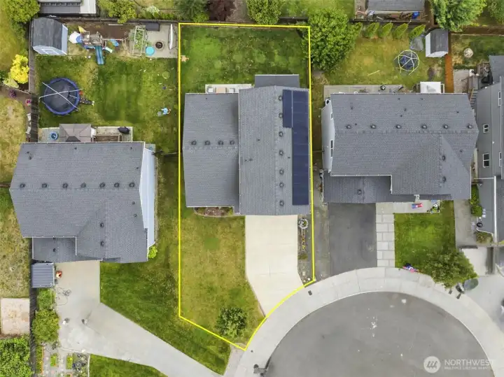 Bird's-eye view showcases the spacious backyard, covered deck, owned solar panels, and beautifully maintained exterior with newer siding and paint.