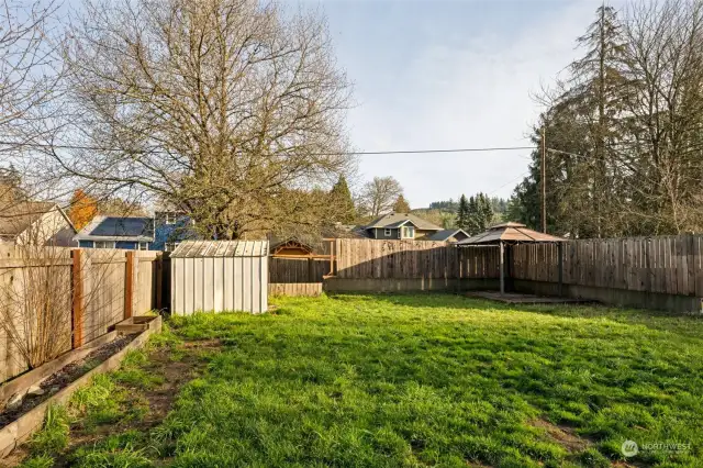 Large backyard with storage shed and garden beds