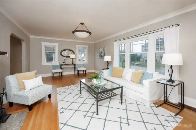 Sunny living room with hardwood floors and wood burning fireplace.