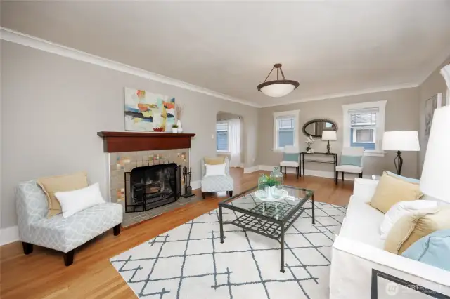 Sunny living room with hardwood floors and wood burning fireplace.