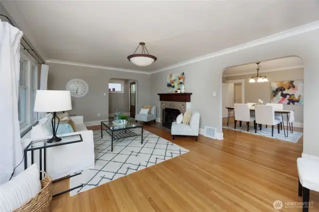 Sunny living room with hardwood floors and wood burning fireplace.
