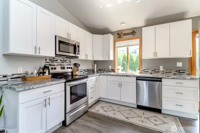 Updated kitchen with white cabinets and granite countertops.
