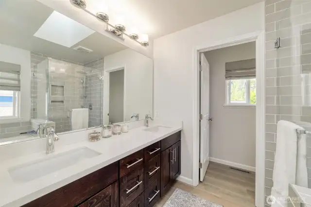 Beautifully updated primary bath features a dual-sink vanity, rich cabinetry, and modern lighting.