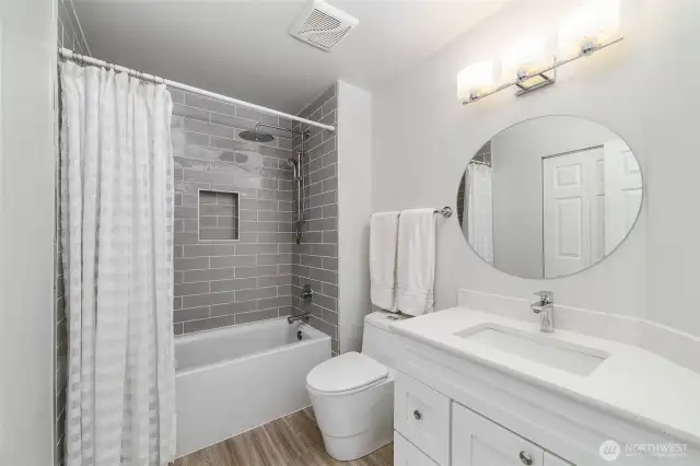 Stylish upper guest bathroom features a modern vanity, sleek lighting, and a tiled shower with built-in inlay