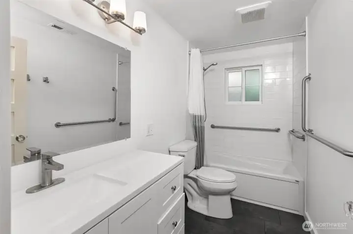 Recently updated bathroom with accessibility grab bars in walls and in the shower, offering modern design, safety, and ease of use