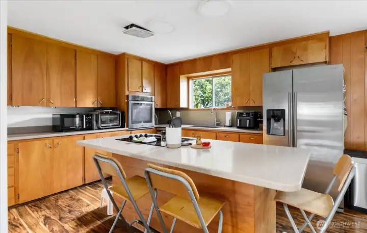 Kitchen features a large island with glass cooktop for entertaining.