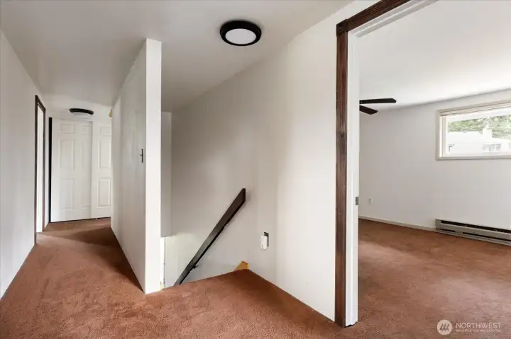 Top of the stairs, with bedroom 1 on the right, and the hallway leading to the primary suite and a full bathroom.