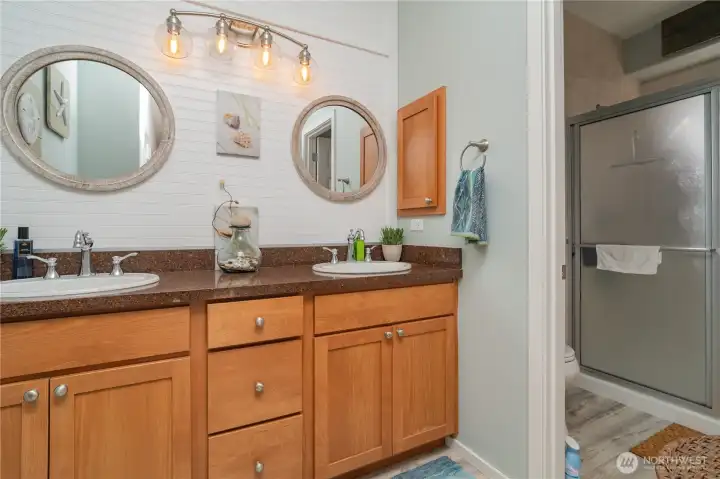 Main bedroom with double sinks and walk in 3/4 shower with tile surround.