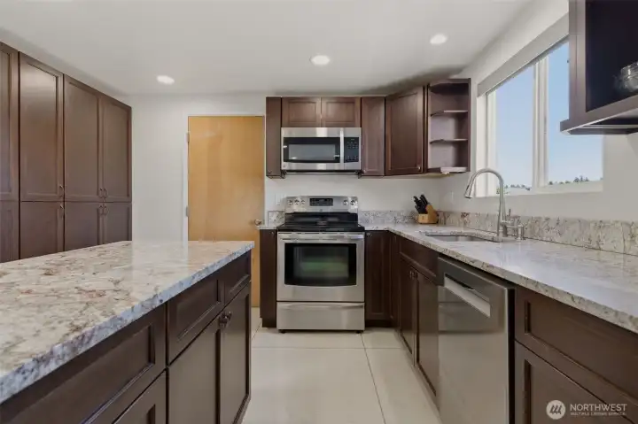 Kitchen features a beautiful slab granite topped island