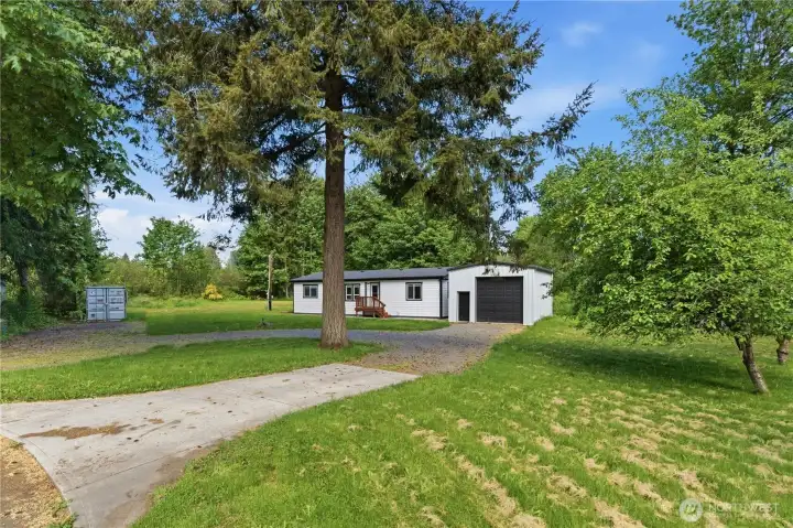 Front view from the cul de sac.  Partial cement driveway to gravel - notice the circular driveway that makes for easy in and out access. This home sits back off the road so will allow you to have total privacy.  Trees, shrubbery and evergreens kiss the landscape and the layout of the property allows an open canvas for a new designs, pool, extra parking and possible large garden area.