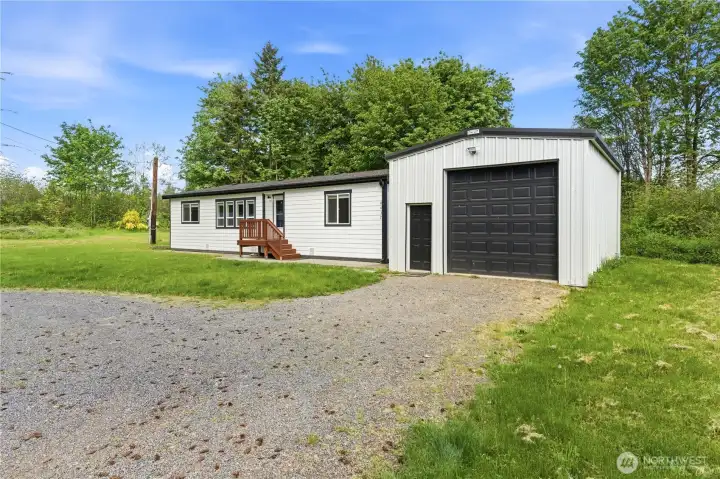 Close up of the 432 sq ft metal shop with oversized insulated garage door, motion lights on exterior and private entry door.