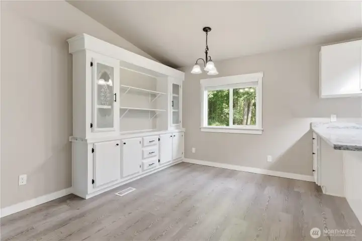 This room is so organized, shelving and cabinetry could offer a breakfast bar, but also allows you extra storage for those bigger kitchen items.  Glass glazed doors flank this beautiful built in. Extended kitchen counter with extra storage could also act as a buffet.   Notice the view out the dining window
