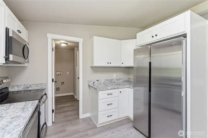 More cabinets, counter top area and a peek a boo view of the laundry area.