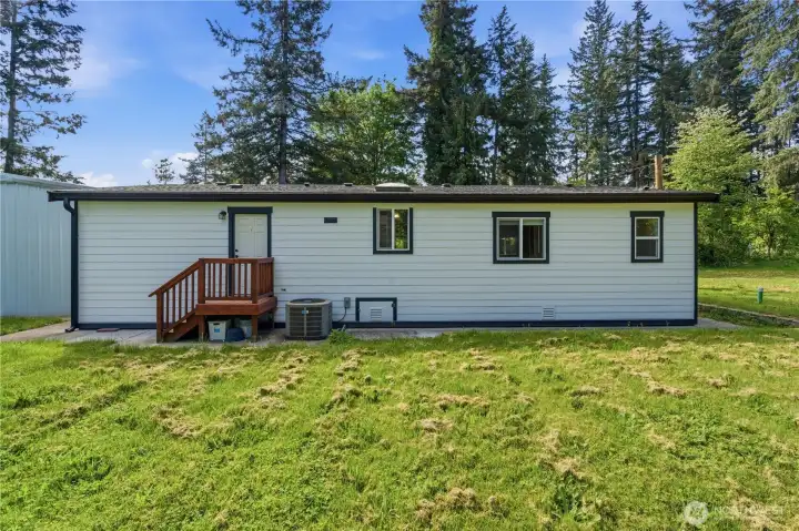 Full view of back , crawl space access and AC unit.  Home has wood siding and composite roof