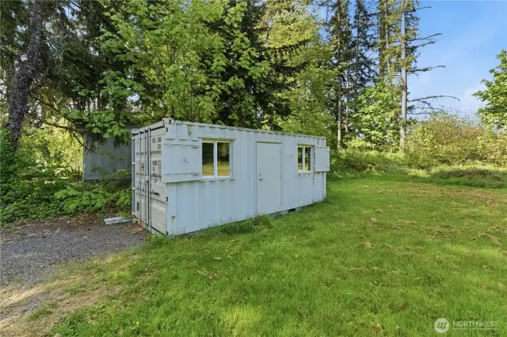 Conex unit/ to the left of the property has metal shutters that cover the windows.  Let this be your DIY project.  Inside has dark plank flooring, is insulated and electrical ruffed in.