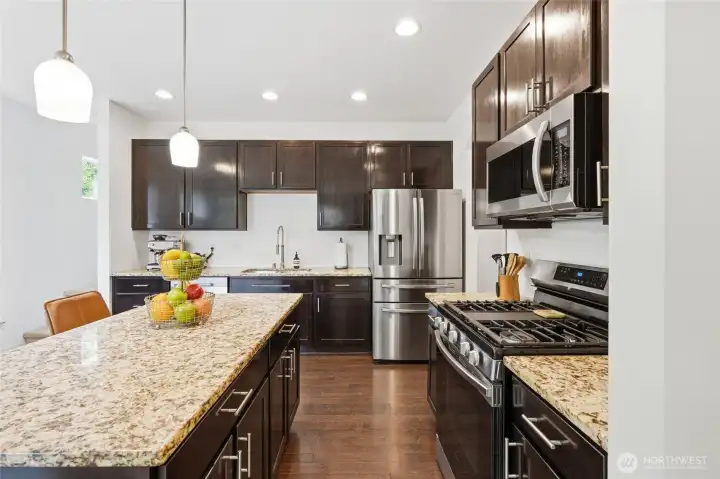The chef-inspired kitchen offers abundant granite countertop space, a large center island, gas range, walk-in pantry, and Samsung Smart Home appliances. The chef-inspired kitchen offers abundant granite countertop space, a large center island, gas range, walk-in pantry, and Samsung Smart Home appliances.