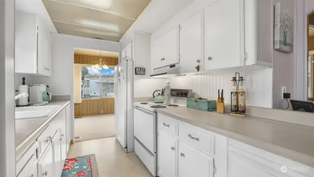 Kitchen features bright cabinetry and matching white appliances.