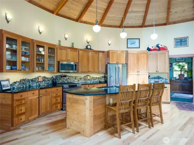 Kitchen, with polished granite island, cherry Shaker-style cupboards, and stone mosaic