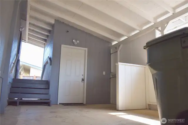 Carport - stairs lead up and over to side "yard"; storage/shop through the door in pic