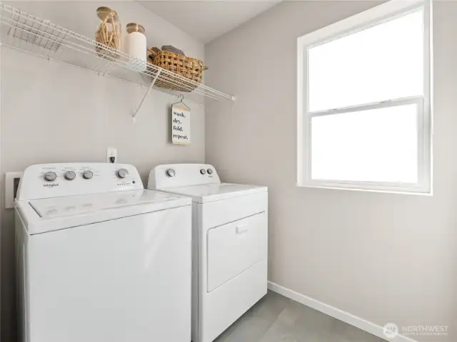 Light-filled upstairs laundry features Whirlpool washer and dryer, durable flooring, and a full-length wire shelf to keep supplies tidy. Pictures are for representational purposes only, colors and features may vary.