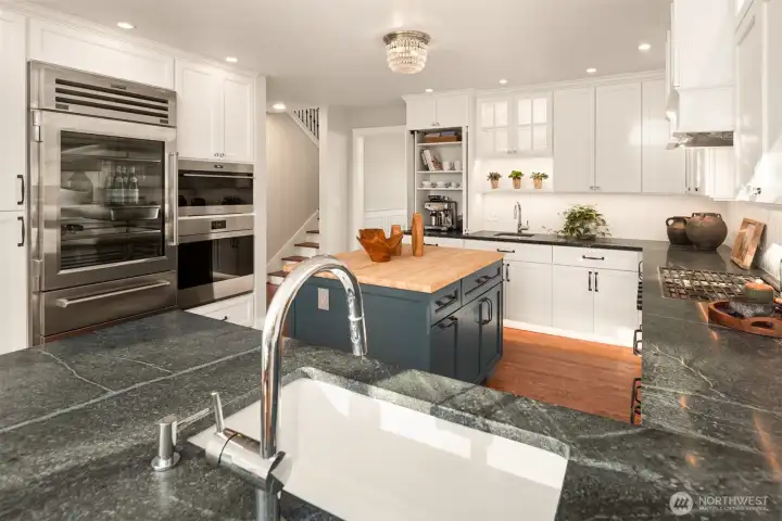 The gourmet kitchen is a chef’s dream, featuring custom cabinetry, rich soapstone countertops, and top-of-the-line appliances from Wolf, Sub-Zero, and Asko. Thoughtful details anticipate every need, with toe kick lighting, double sinks, and touch activated faucet
