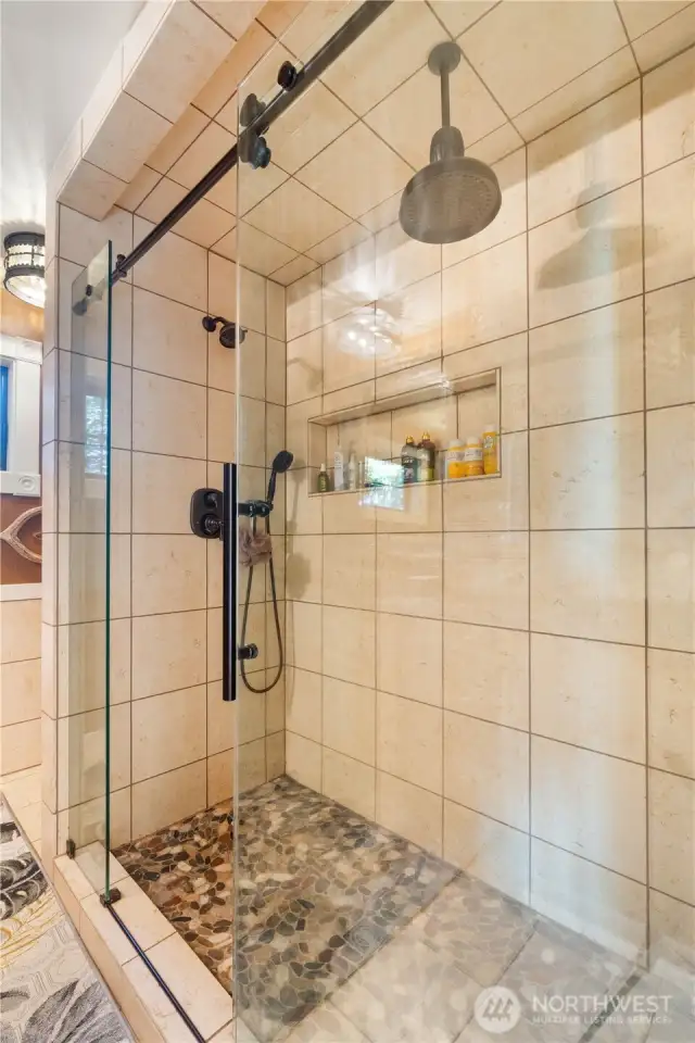 2nd bathroom huge walk in shower with rain shower head, tile surround and pebble tile floors