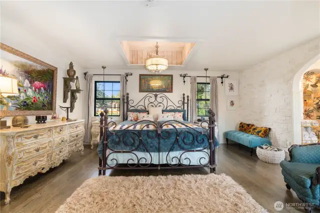 Primary Bedroom w/hardwood floors, lots of natural light, and floor to ceiling stone accent wall and entry to the primary bathroom