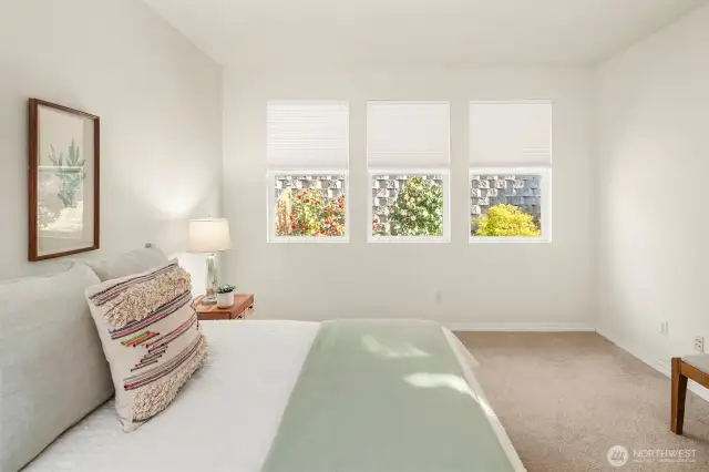 Well lit primary bedroom with custom blinds.