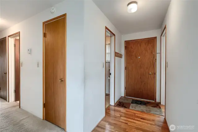 The door to the furthest right is toward the kitchen, the next one is the entry door, with security hole.  to the left of that is the guest bathroom.  then down the hall is a coat closet, then the full bathroom then a linen closet.  the thermostat is on the wall.