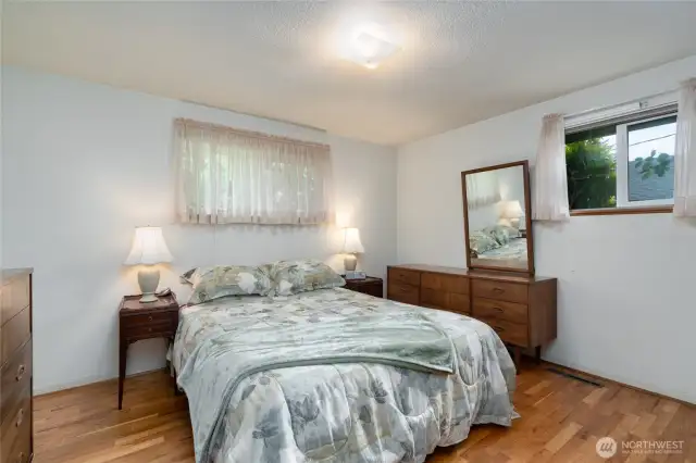 Primary bedroom with view of the back and side yard.  Hardwood floors.