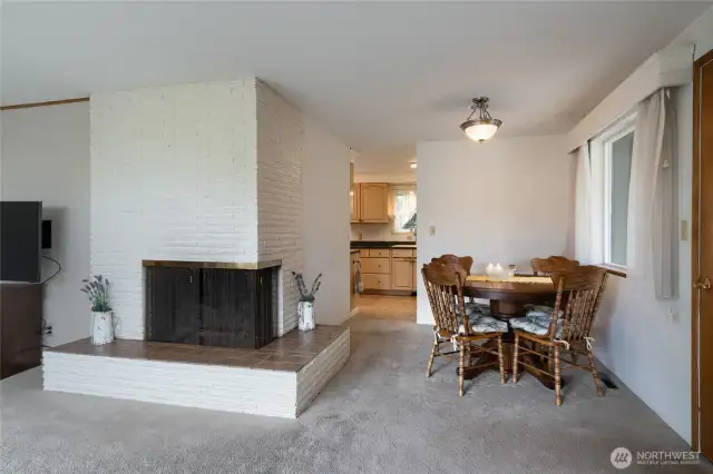 dining room, peek of the kitchen, fireplace, and access to the sun room.