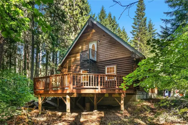 This is the back of the home showing large, entertaining sized deck and beautiful iron staircase leading to upper level