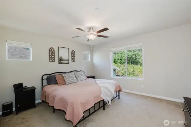 Primary bedroom with ceiling fan and natural light.