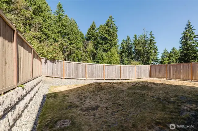 Private fenced backyard with retaining wall.