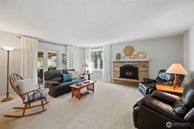 Across from the den at the entry is this luxurious living room with new carpet, eletric fireplace element with seating hearth, and glass doors to the deck out back.