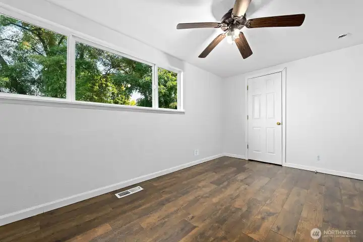 Bright and airy with large windows, this cozy bedroom is finished with rich wood flooring and a ceiling fan for comfort.