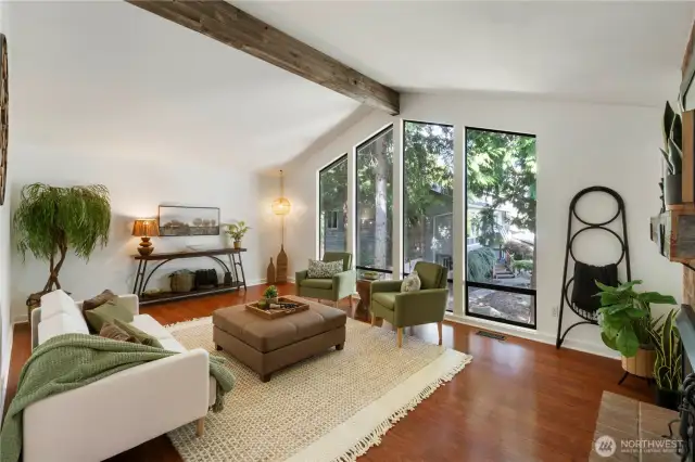 Step into this impressive living room where soaring vaulted ceilings create an airy sense of openess, the beam adds warmth and charm, and the wall-to-floor windows add a unique frame to the outside world.