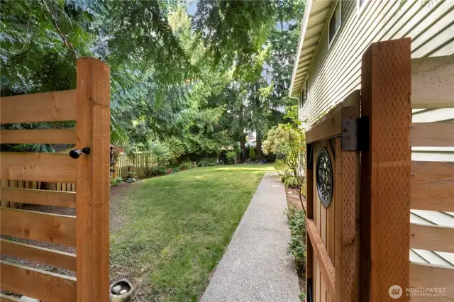 Step though the gate from the sideyard into the backyard, where you'll enjoy the privacy of the mature trees & plantings.